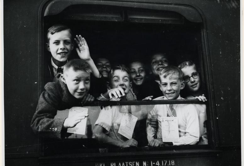 Kinderen hangend uit het raam van een trein in het station Delftse Poort