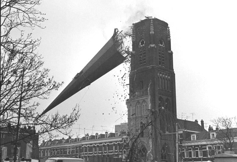 foto van een kerktoren dat naar beneden valt tijdens de sloop van het gebouw