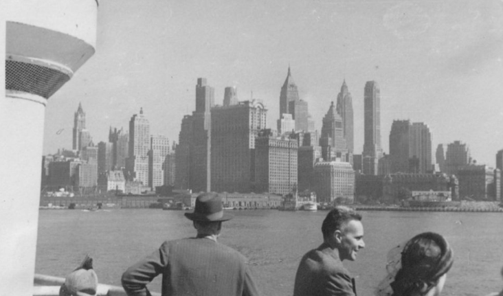 Jan Tinbergen van de zijkant gefotografeerd aan dek. Op de achtergrond New York