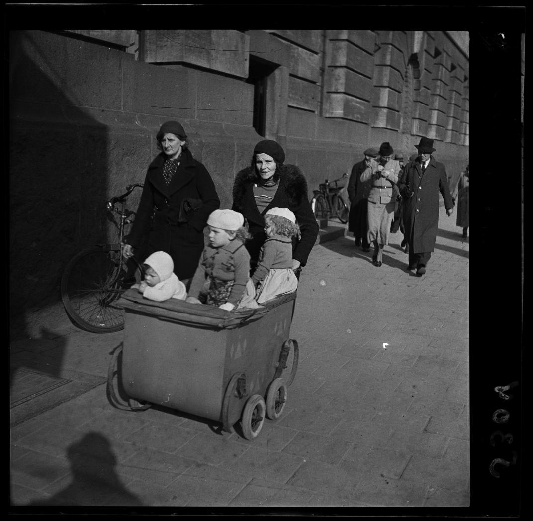 Een vrouw loopt met een kinderwagen met drie kinderen langs het postkantoor aan de Coolsingel. Foto uit de collectie Spaarnestad