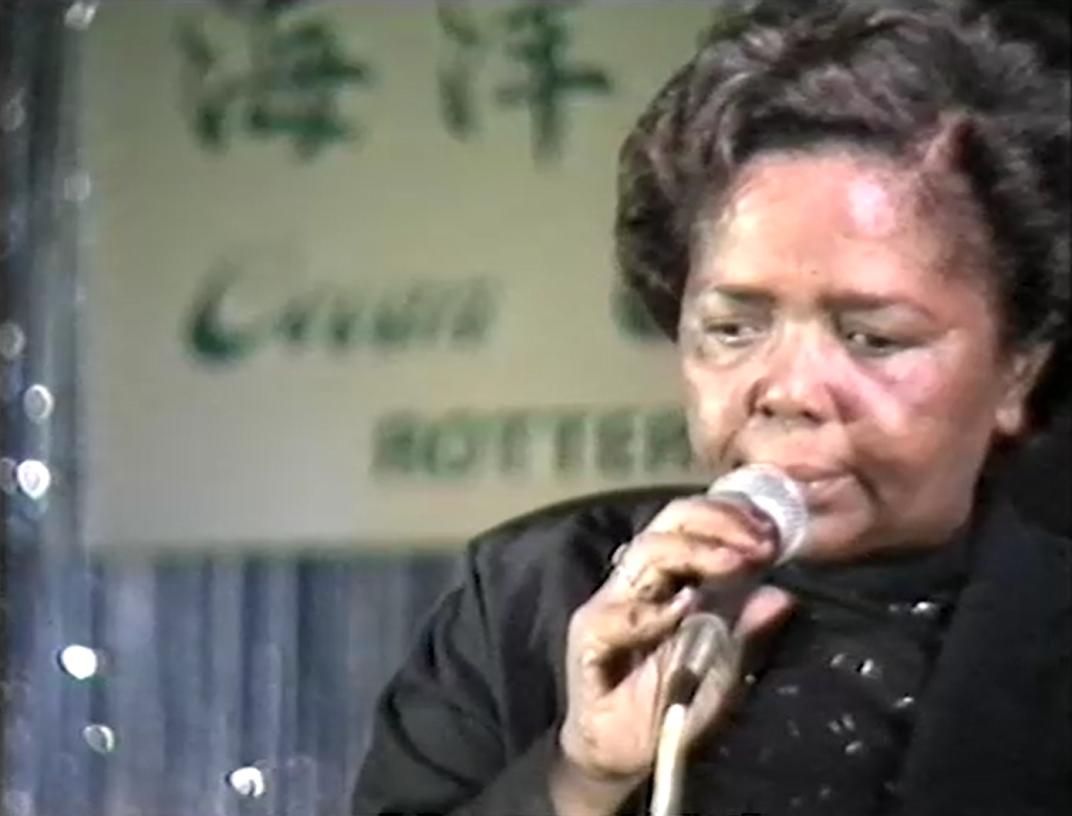 Een screenshot van de uitzending van TV Mozaïek van 27 oktober 1988. Cesária Évoria is te zien met microfoon tijdens het concert in de Nieuwe Ocean Paradise.