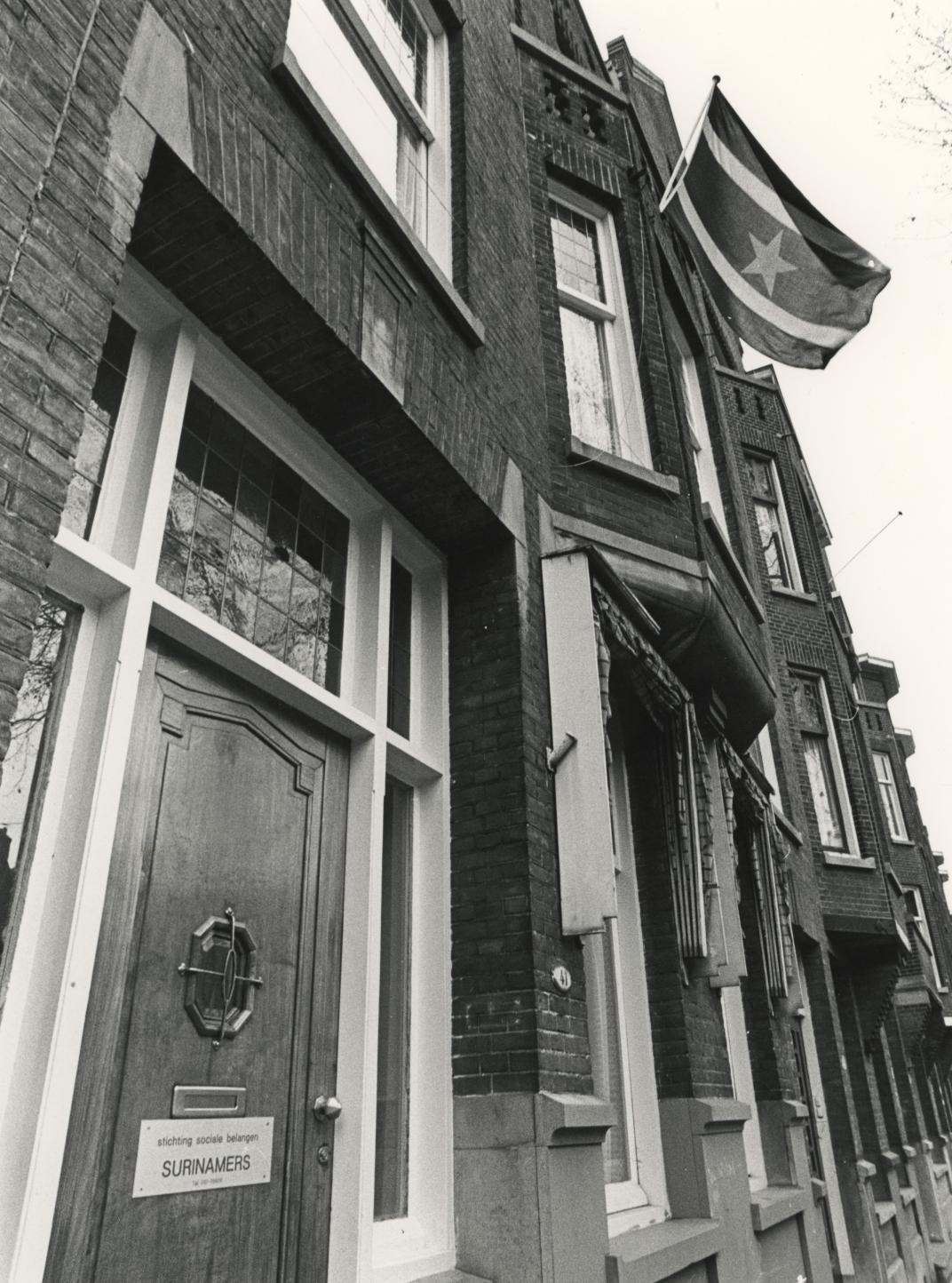 Zwart foto van herenhuis met Surinaamse vlag opgestoken