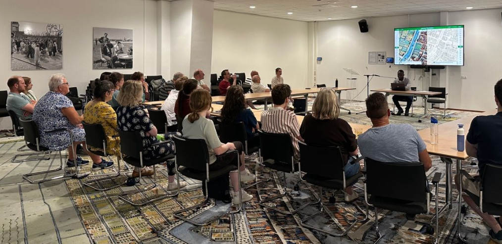 Foto van een groep mensen in een zaal bij Stadsarchief Rotterdam tijdens een presentatie
