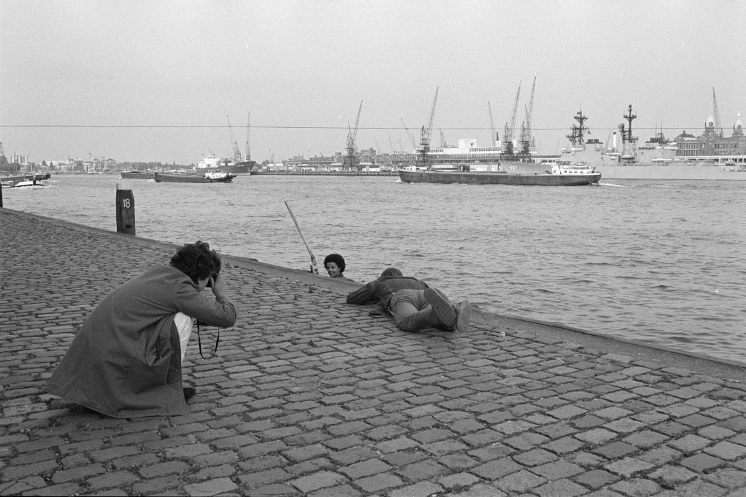 Fotograaf Eric van der Schalie ligt op de Wiilemskade om een model te fotograferen voor het boek 'Die stad komt nooit af'.