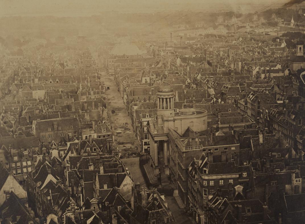 Zicht vanaf de Laurenstoren op het oostelijk deel van de binnenstad. In het midden is de Kaasmarkt met het stadhuis te zien. Onder de koepel naast de toren bevindt zich de Rotondezaal. Collectie Vroege foto's. NL-RtSA_4187_RI-248a