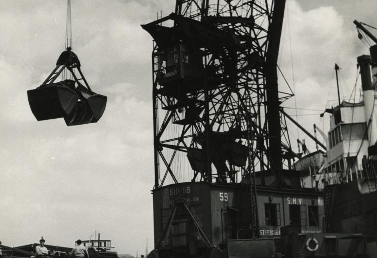 De kolentransporteur SHV 59 verplaatst de kolen van een kolenschip naar een vrachtschip (1920).