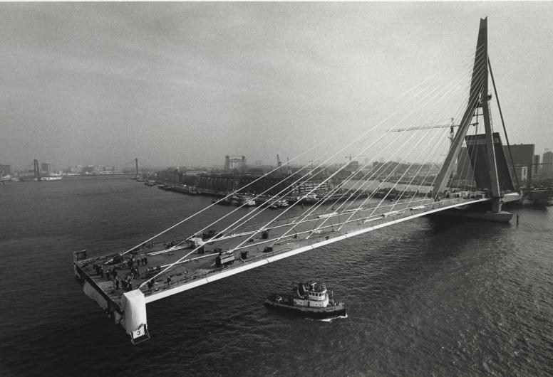 De Erasmusbrug in aanbouw. Zicht op de Nieuwe Maas met de pyloon en een aantal brugdelen in zuidoostelijke richting. Op de achtergrond het Noordereiland. Hajo Piebenga 1996. Collectie 4110, nummer 2249