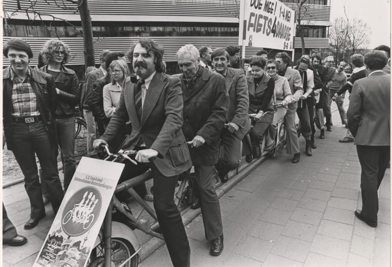25 april 1978: Het College van Burgemeester en Wethouders maken reclame voor de Rotterdamse fietsvierdaagse op 1,2,3, en 4 mei 1978. Het gezelschap poseert op een elfpersoonsfiets voor het Gemeentelijk Rekencentrum aan de Stationssingel. Op de foto o.a. burgemeester André van der Louw, de wethouders J.G. van der Ploeg, Mentink, Schmitz, Van der Have, Riezenkamp, Mastik en Van der Pols. Foto: Rotterdams Nieuwsblad. Collectie 4282, 1978-1370-kl