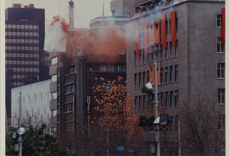 Met oranje versierde gebouwen, oranje ballonnen en rook. Koninginnedag 1992, bezoek aan Rotterdam (o.a. Overschie). Het album is afkomstig uit het archief van Bram Peper. 