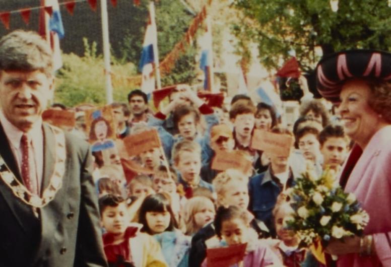 Koningin Beatrix langs een stoet mensen. Naast haar staat Burgemeester Peper