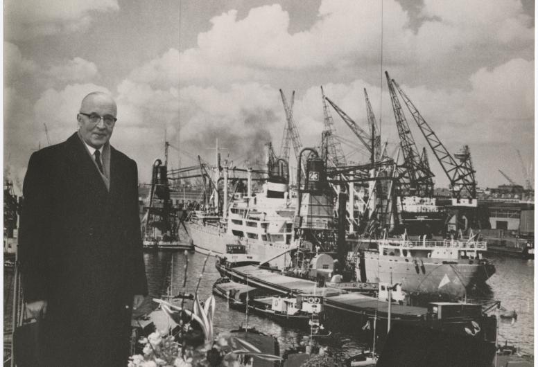 Omstreeks 1960: Portret van burgemeester Van Walsum langs de kade van de Maashaven. Op de achtergrond lossen graanzuigers de lading van een schip. Tom Kroeze / auteursrechthouder Johan Aarssen Fotografie. Collectie 4031_P-008424-23-KL.