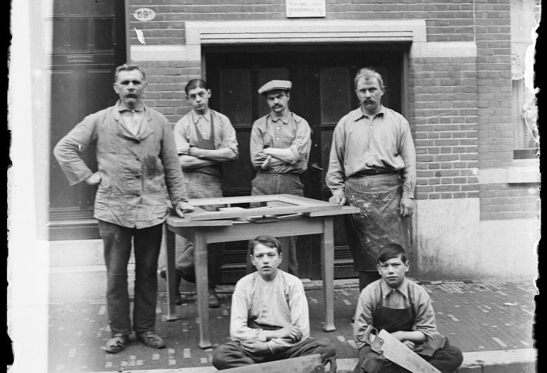 De heer Peiffer poseert met medewerkers en gereedschap voor de tafelmakerij A.A. Peters, gevestigd aan de Vredenoordkade.