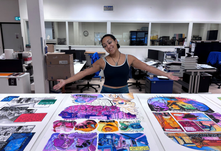 Foto van artieste AMBIGOU met voor haar op tafel haar tekeningen