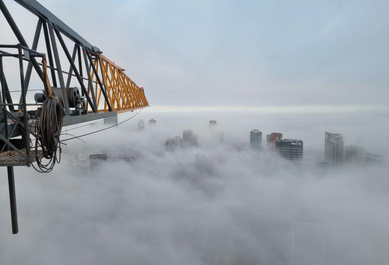 Luchtfoto in noordelijke richting in de mist vanuit de werkbak van een kraan tijdens de bouw van de Cooltoren. 