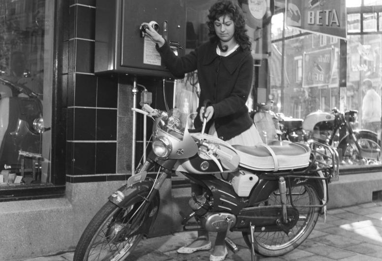 Een vrouw tankt brandstof voor de bromfietsmotor bij een '2 takt automaat' van bromfietsverkoper Willy van Gent aan de Bergweg 210.