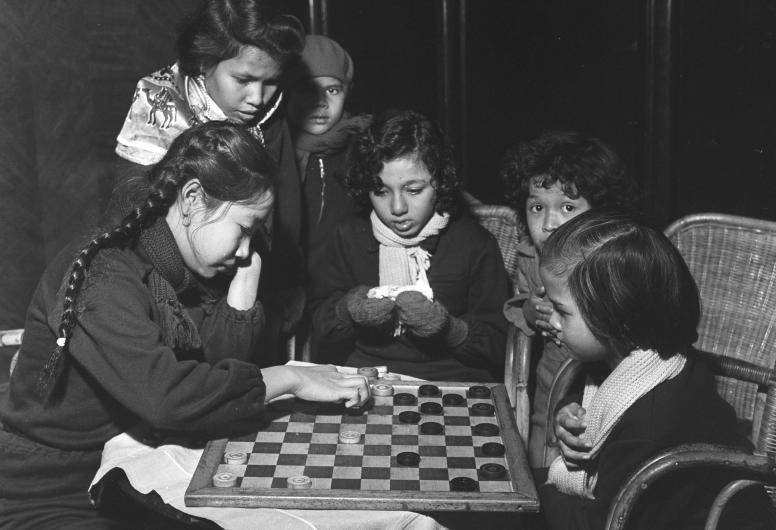 Kinderen uit Indonesië aan boord van het passagiersschip 'Sibajak' van de Koninklijke Rotterdamsche Lloyd aan de Lloydkade. De kinderen spelen een damspel. 19 januari 1958.