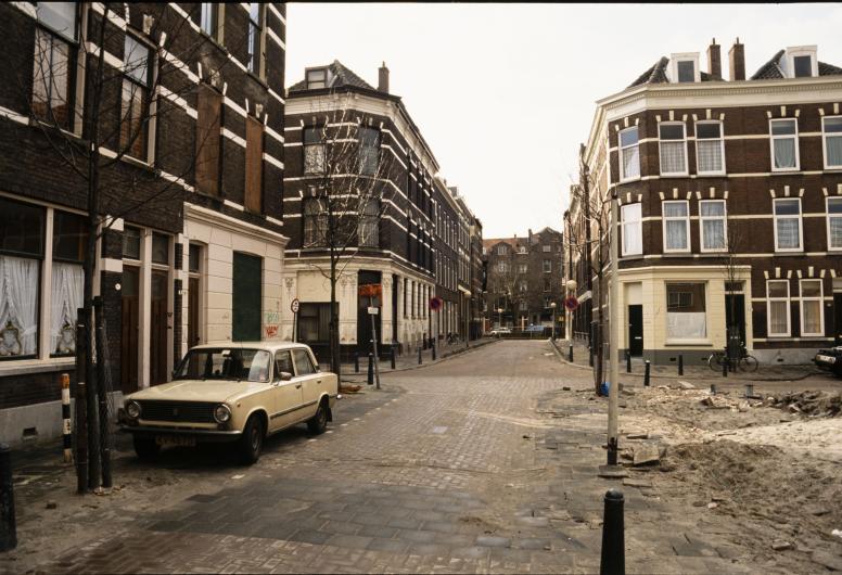 De kruising Akeleistraat en de Zijdewindestraat in het Oude Westen. Op de achtergrond de Henegouwerlaan. Rechts een braakliggende stukje stad. 28 februari 1988