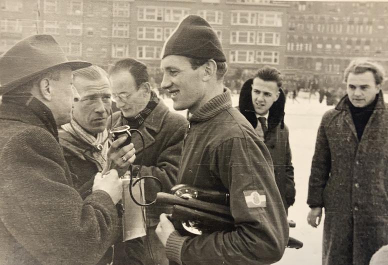 Nederlandse schaatser Kees Broekman uit De Lier wordt geïnterviewd door radioverslaggevers tijdens internationale schaatswedstrijden op het terrein van IJsclub Kralingen. Uit het Fotoarchief van IJsclub Kralingen Toegang 255 Inventarisnummer 124.