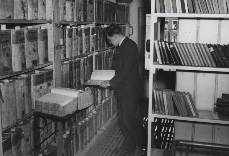 Interieurfoto van depot 1 met een medewerker of een bezoeker. 1947 Collectie Topografie. NL-RtSA_4202_XXI-19-03.