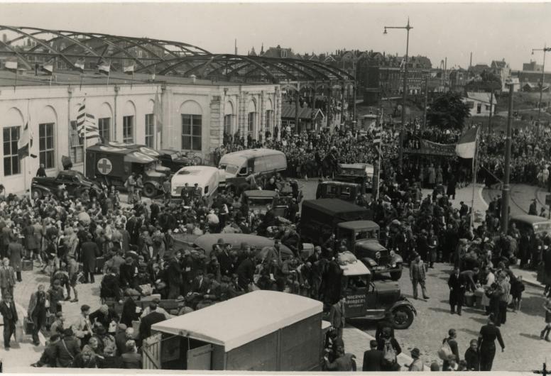 Dwangarbeiders die zijn teruggekeerd uit Duitsland verzamelen zich op het plein voor Station Delftse Poort, 2 juni 1945. Fotograaf H. van Langelaar.