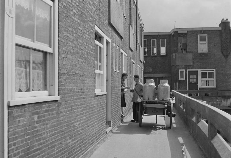 Melkboer met kar over de galerij van het Justus van Effencomplex. 1950 NL-RtSA_4204_3318. Collectie Gemeentewerken