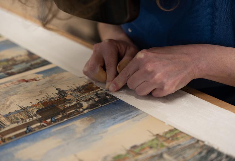 Maaike Heemskerk verwijdert het oude passe-partout met een scalpel.