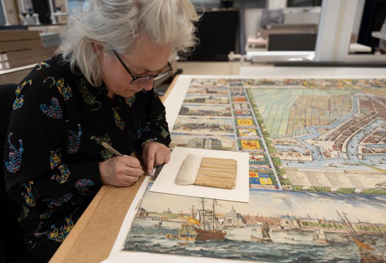 Miranda Demuijnck verwijdert met een scalpel lijmresten van het passe-partout.