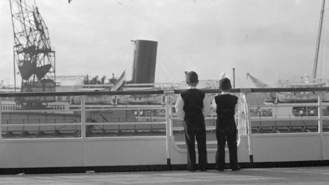 Twee jongens op het dek van ms. 'Willem Ruys', kijken naar ms.'Sibajak'. Fotograaf Ary Groeneveld, collectie 4121, nummer 123-01