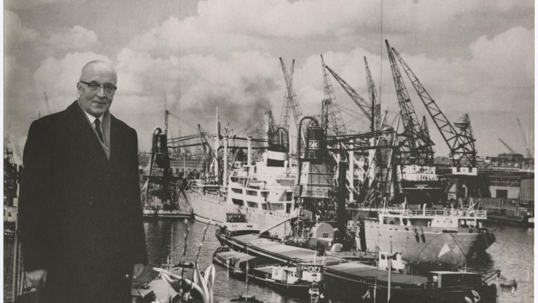 Omstreeks 1960: Portret van burgemeester Van Walsum langs de kade van de Maashaven. Op de achtergrond lossen graanzuigers de lading van een schip. Tom Kroeze / auteursrechthouder Johan Aarssen Fotografie. Collectie 4031_P-008424-23-KL.