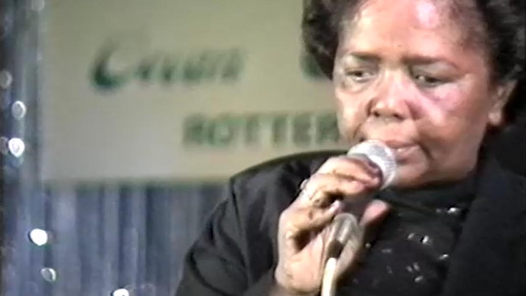 Een screenshot van de uitzending van TV Mozaïek van 27 oktober 1988. Cesária Évoria is te zien met microfoon tijdens het concert in de Nieuwe Ocean Paradise.