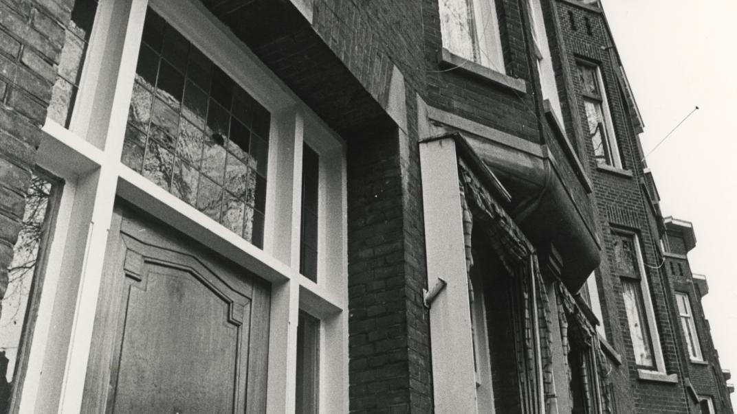 Zwart foto van herenhuis met Surinaamse vlag opgestoken